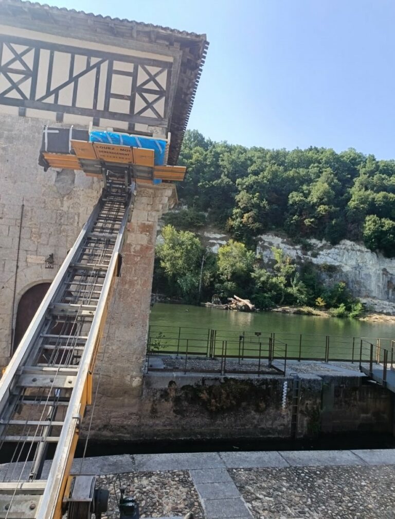 Monte-charge etoile longeant un ancien bâtiment en pierre au bord d’une rivière dans le tarn