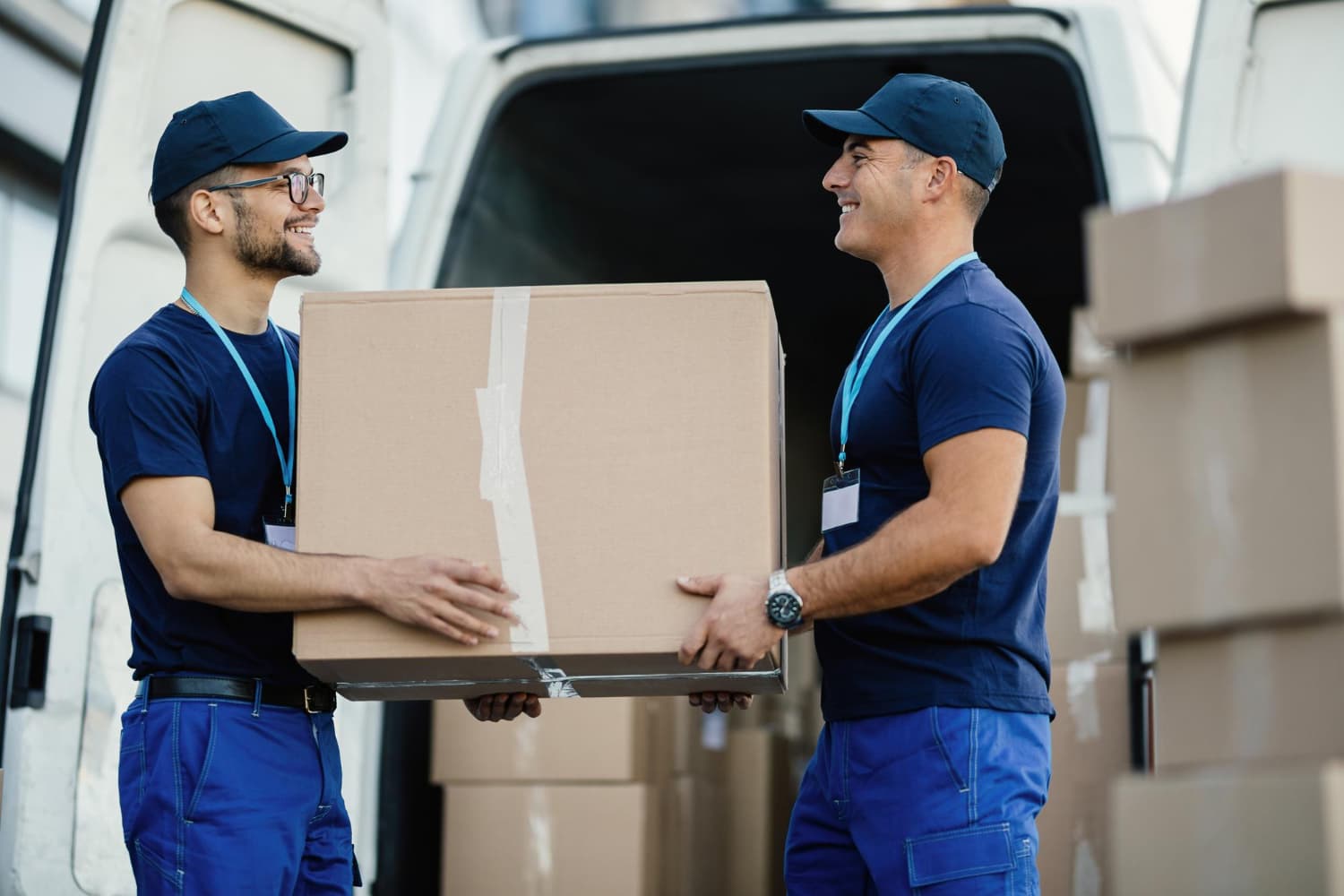 Déménageurs etoile en uniforme bleu portant un carton devant une camionnette dans le tarn